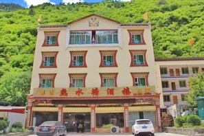 Um edifício de vários andares com estilo arquitetônico tradicional, destacando uma entrada imponente com toldo decorativo e uma placa.