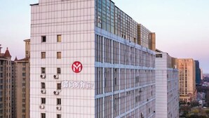 Un immeuble de grande hauteur à la façade quadrillée, doté de nombreuses unités de climatisation et arborant un logo bien visible sur le côté.