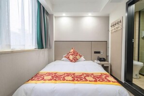 A hotel room with a bed, a nightstand, a mirror, and a window with curtains.