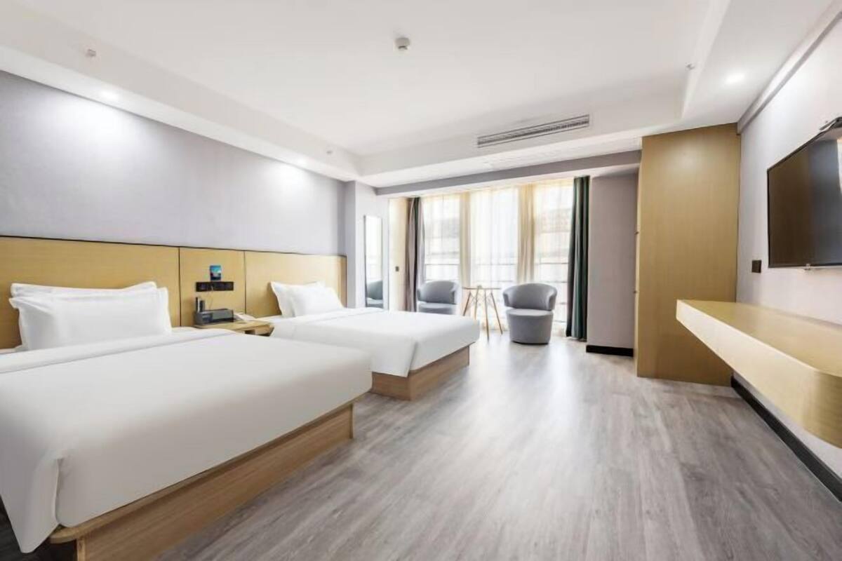 Une chambre d’hôtel avec deux lits, un bureau, une chaise et une télévision.