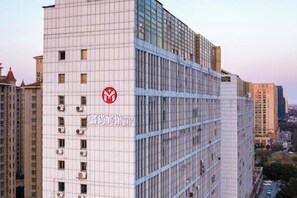 Un edificio de varios pisos con fachada enrejada, unidades de aire acondicionado y un logotipo lateral.