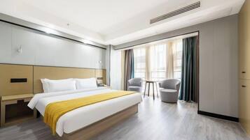 A hotel room with a large bed, a desk, two chairs, and a view of the outdoors.