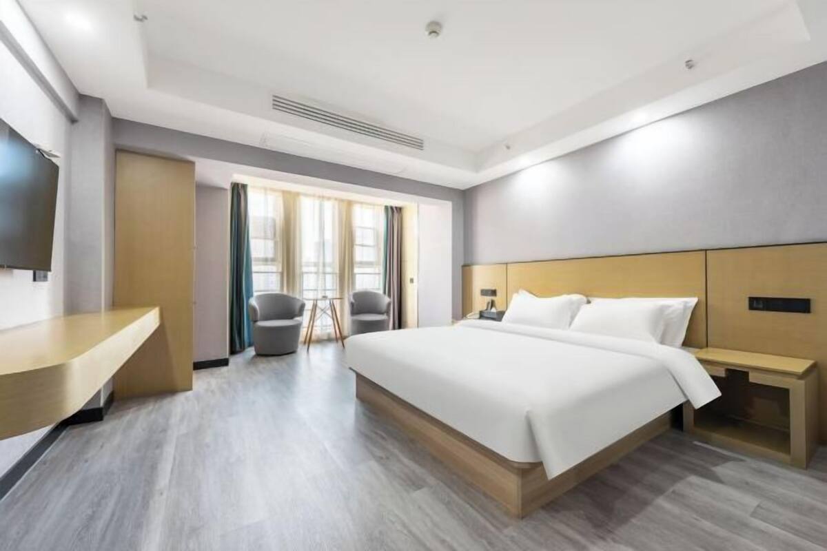 Une chambre d’hôtel moderne équipée d’un grand lit, d’un bureau, d’une chaise et d’un téléviseur.