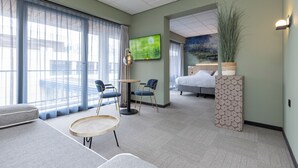 A hotel room with a bed, two chairs, a small table, a TV, and a large window with curtains. - Fletcher Hotel-Restaurant Marknesse (Marknesse)