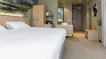 Une chambre d’hôtel avec un grand lit, un bureau avec un miroir, une machine à café et un tableau au mur.