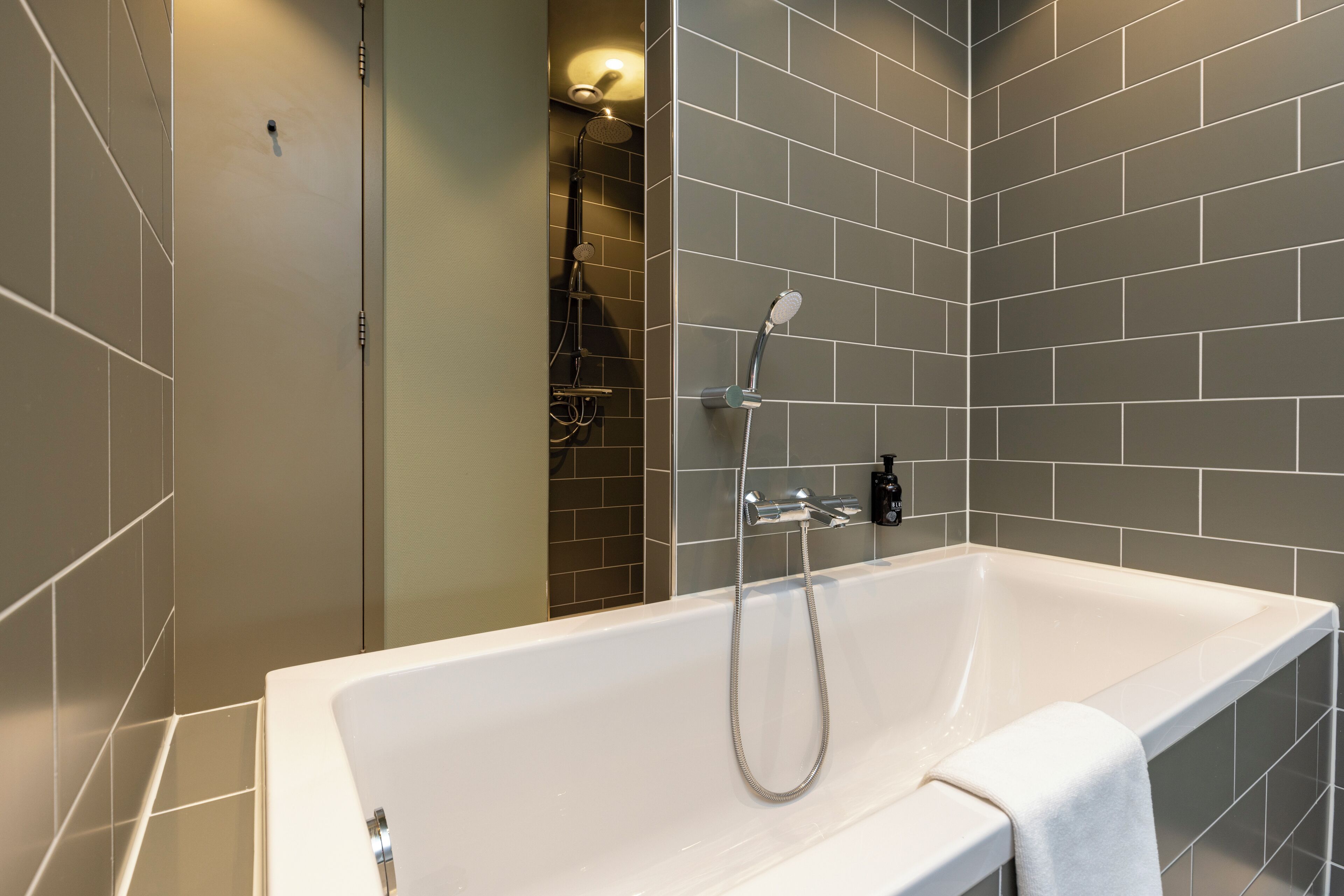 A modern bathroom with a large bathtub, a shower area, and tiled walls.