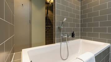 A modern bathroom with a large bathtub, a shower area, and tiled walls.