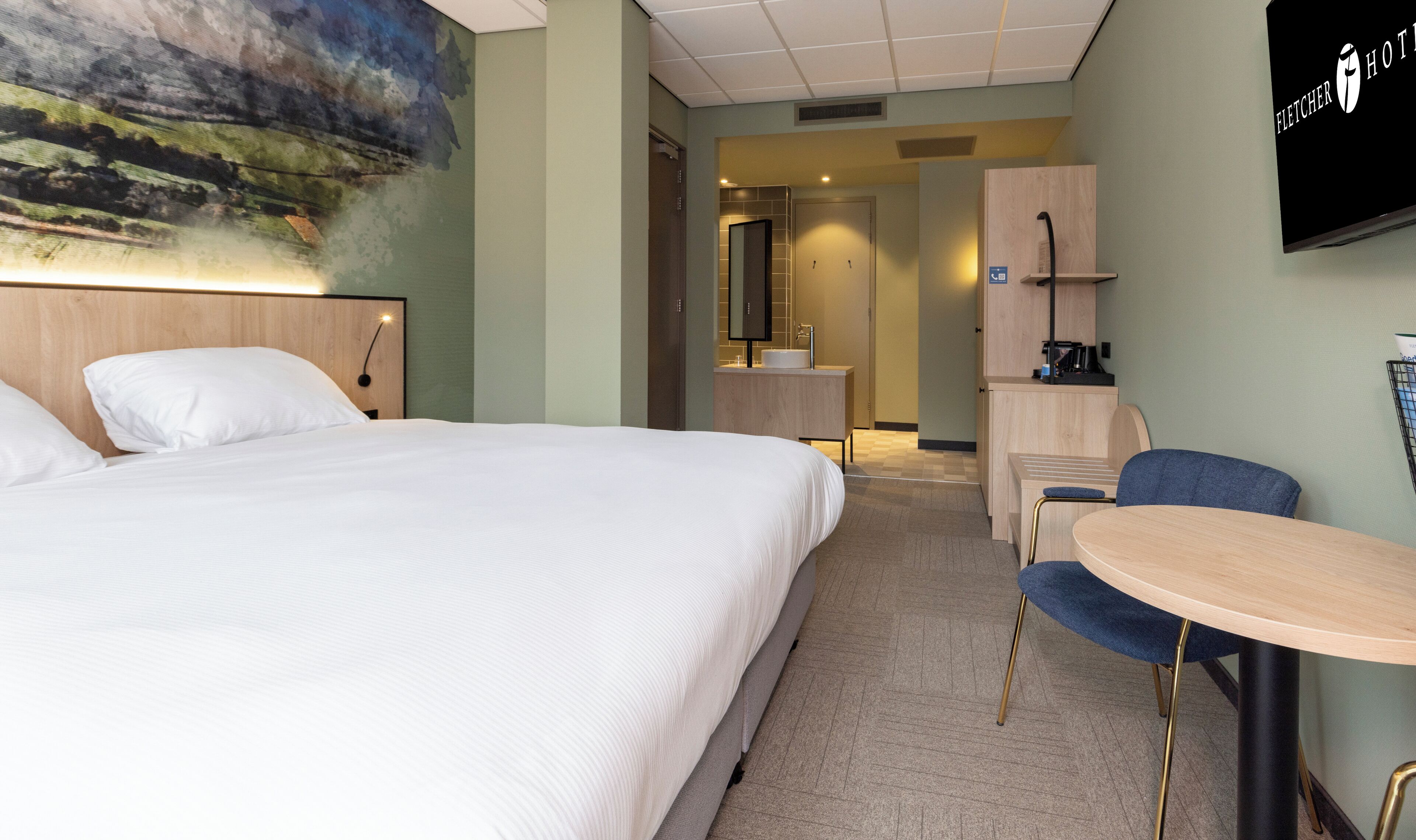 Habitación de hotel con cama, escritorio, silla y televisor.