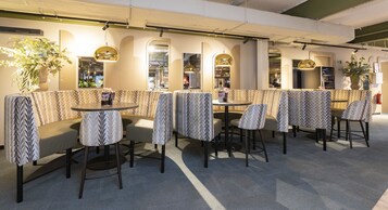 Un restaurante moderno con asientos tipo cabina estampados y mesas redondas.