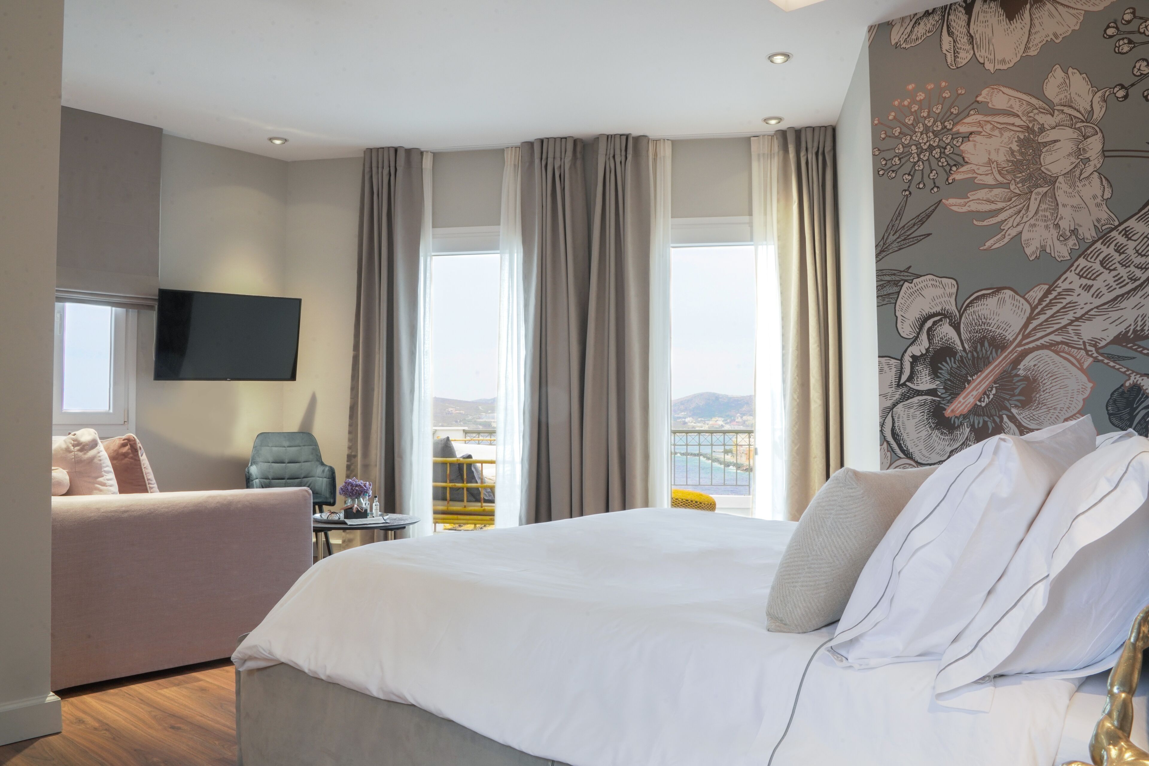 Una habitación de hotel con una cama grande, un sofá, un televisor y un balcón con vistas.