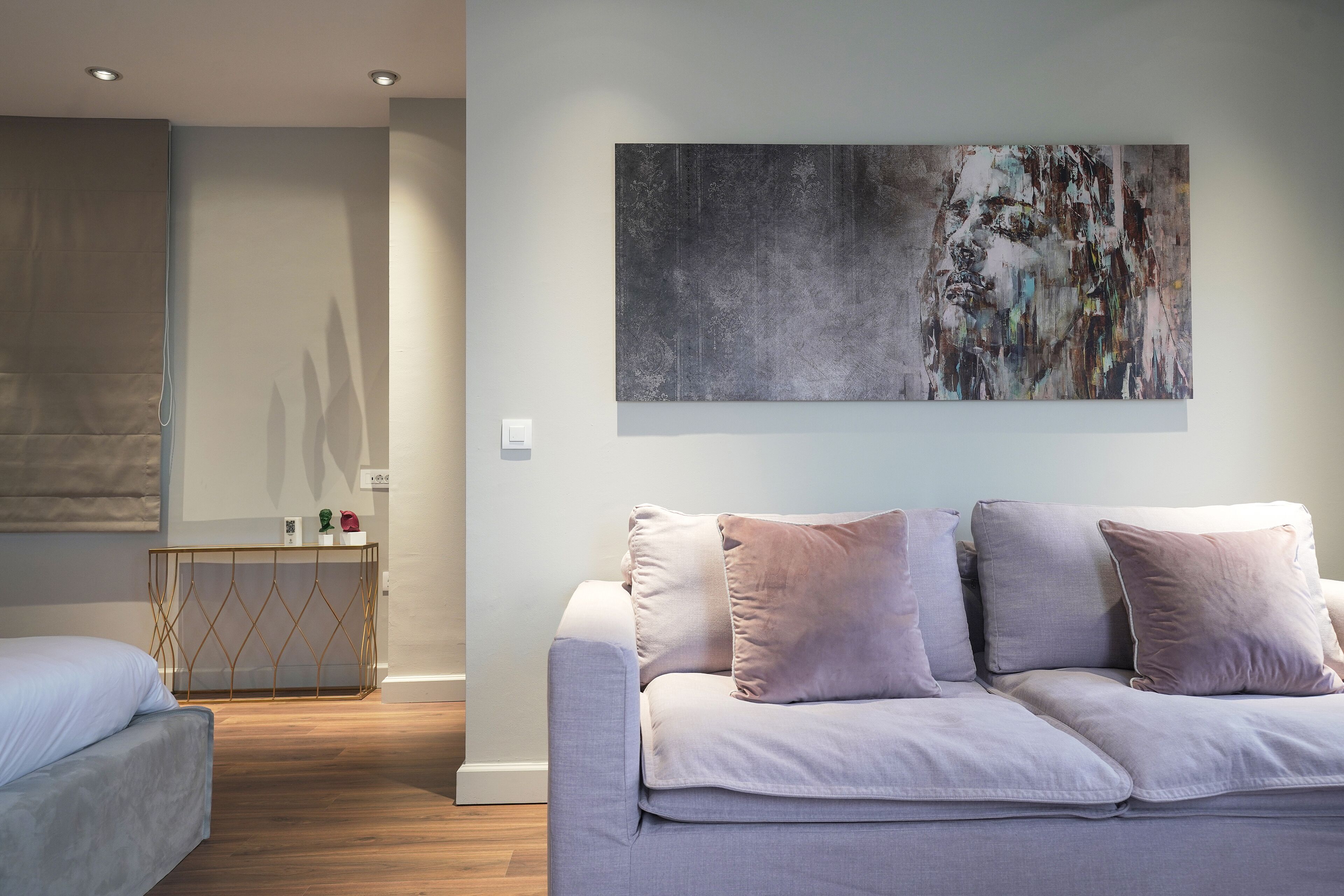 A modern living room with a grey sofa, a console table, and a large abstract painting on the wall.