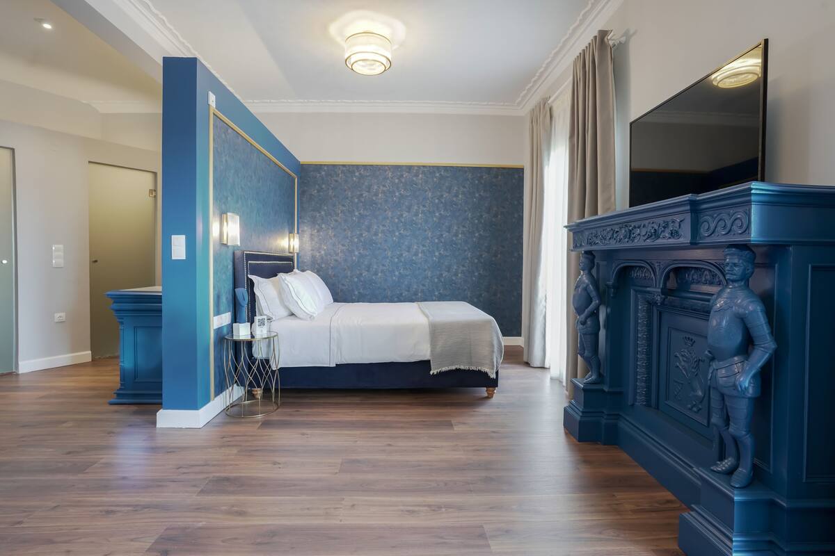 A bedroom with a bed, a nightstand, a dresser, and a large mirror.