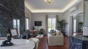 A spacious living room with a marble fireplace, a round dining table, and a comfortable sofa. - Pafsilipon Suites (Syros)