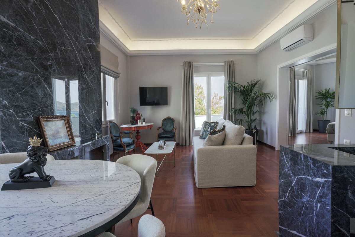 A spacious living room with a marble fireplace, a round dining table, and a comfortable sofa.