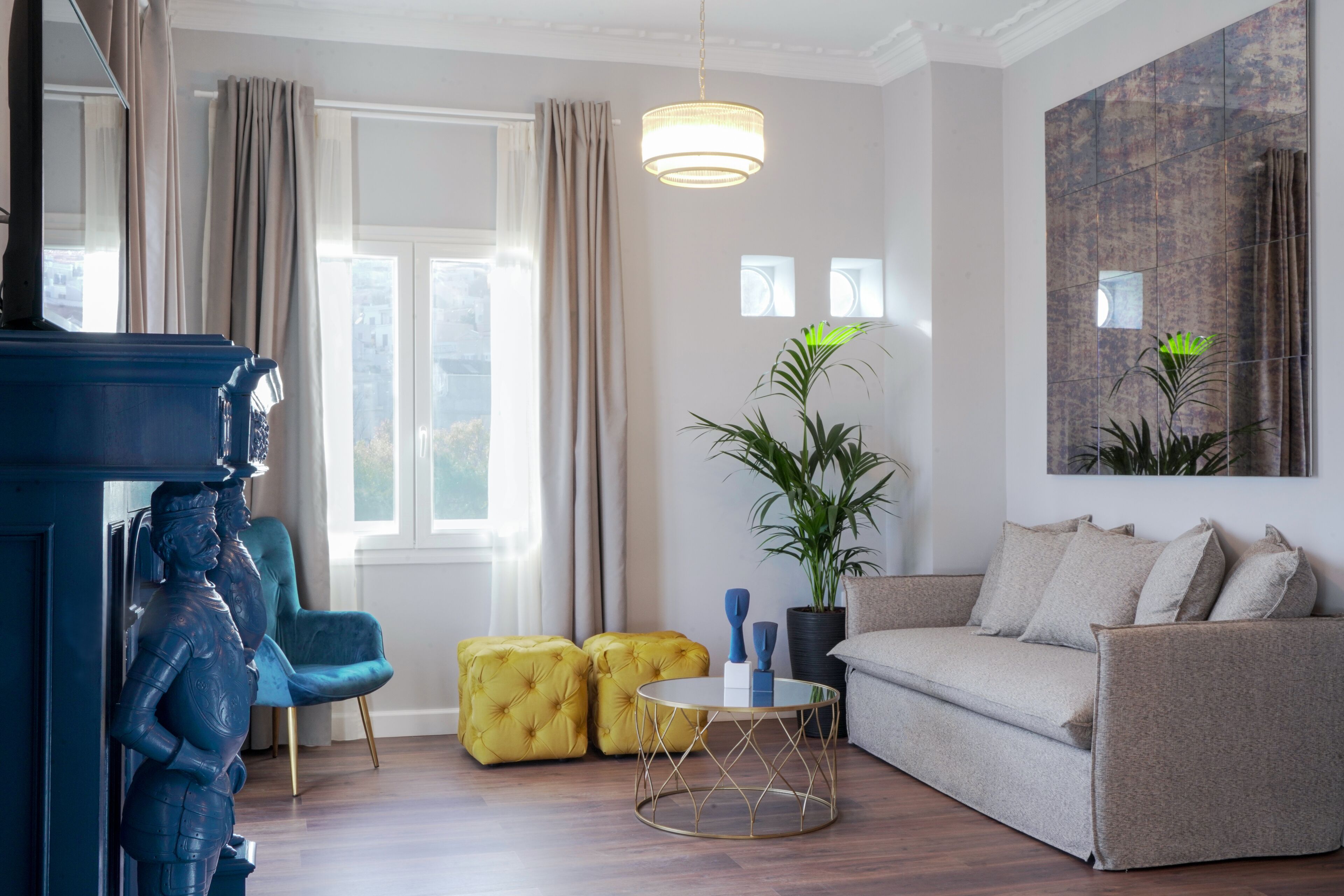 A modern living room with a sofa, ottomans, a coffee table, and a large potted plant.