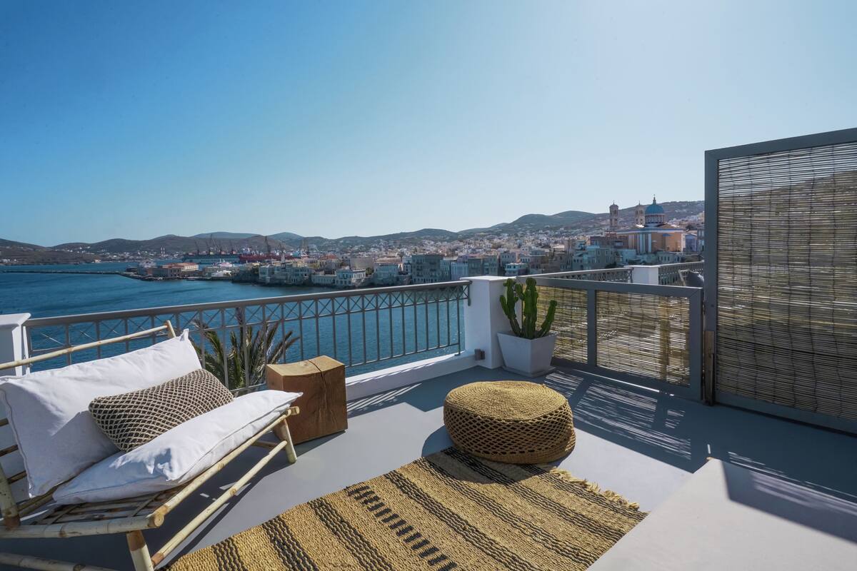 A balcony with a view of the sea and a cityscape.