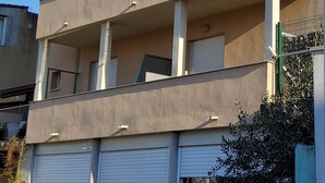 Un edificio de varios pisos con balcones, un garaje y una pila de ladrillos.