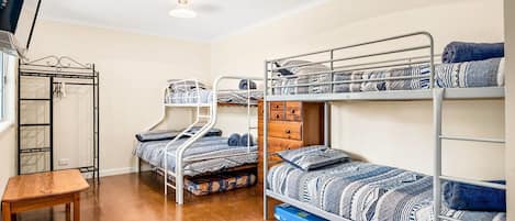 A dormitory room with bunk beds, a wooden table, and a wardrobe.