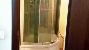 Ein Eckzimmer mit einem Glastisch-Drehsessel, Holzboden und einer weißen Tür.