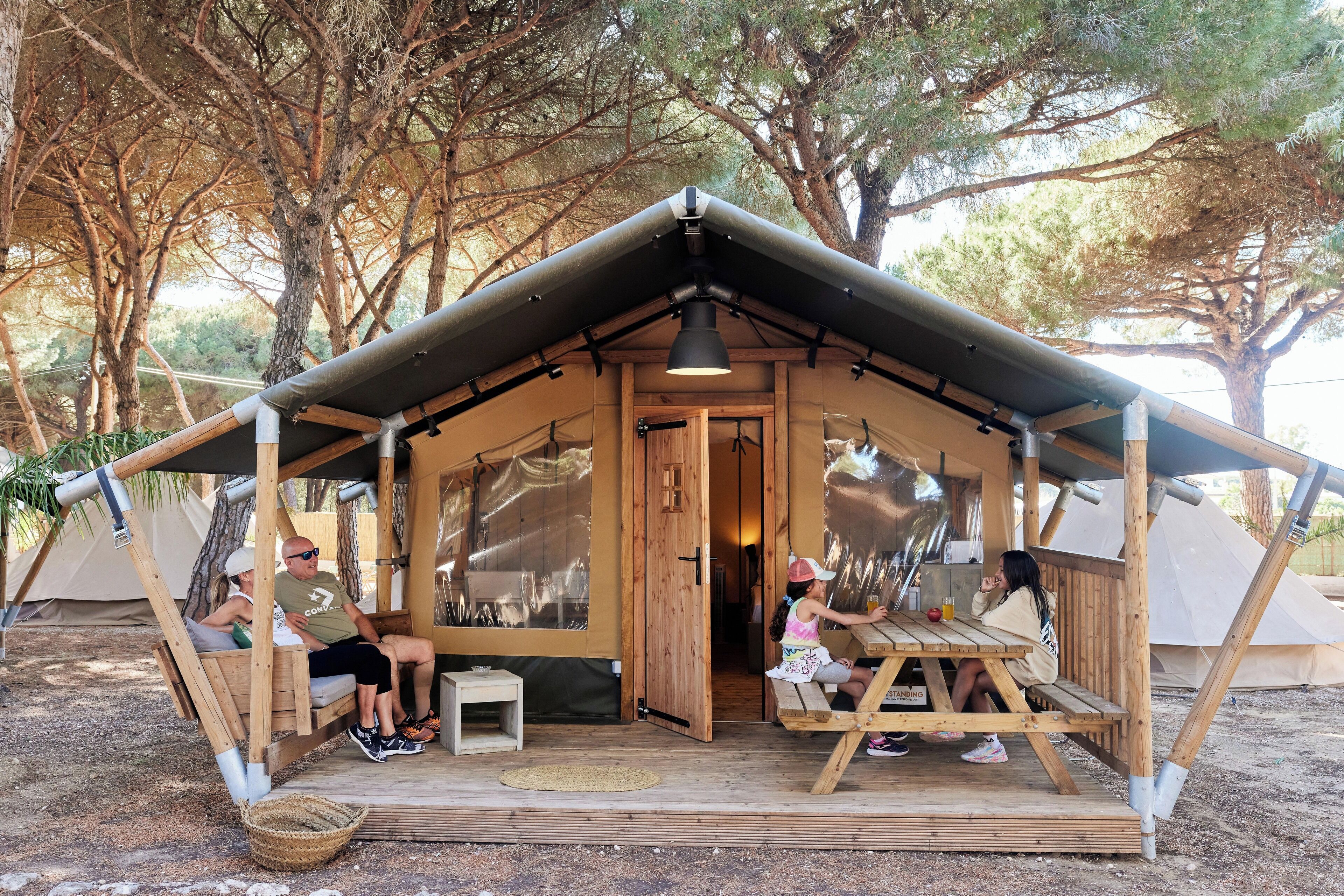 A wooden cabin with a porch, a dining table, and a bench.