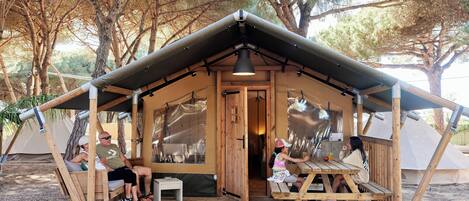 A wooden cabin with a porch, a dining table, and a bench.