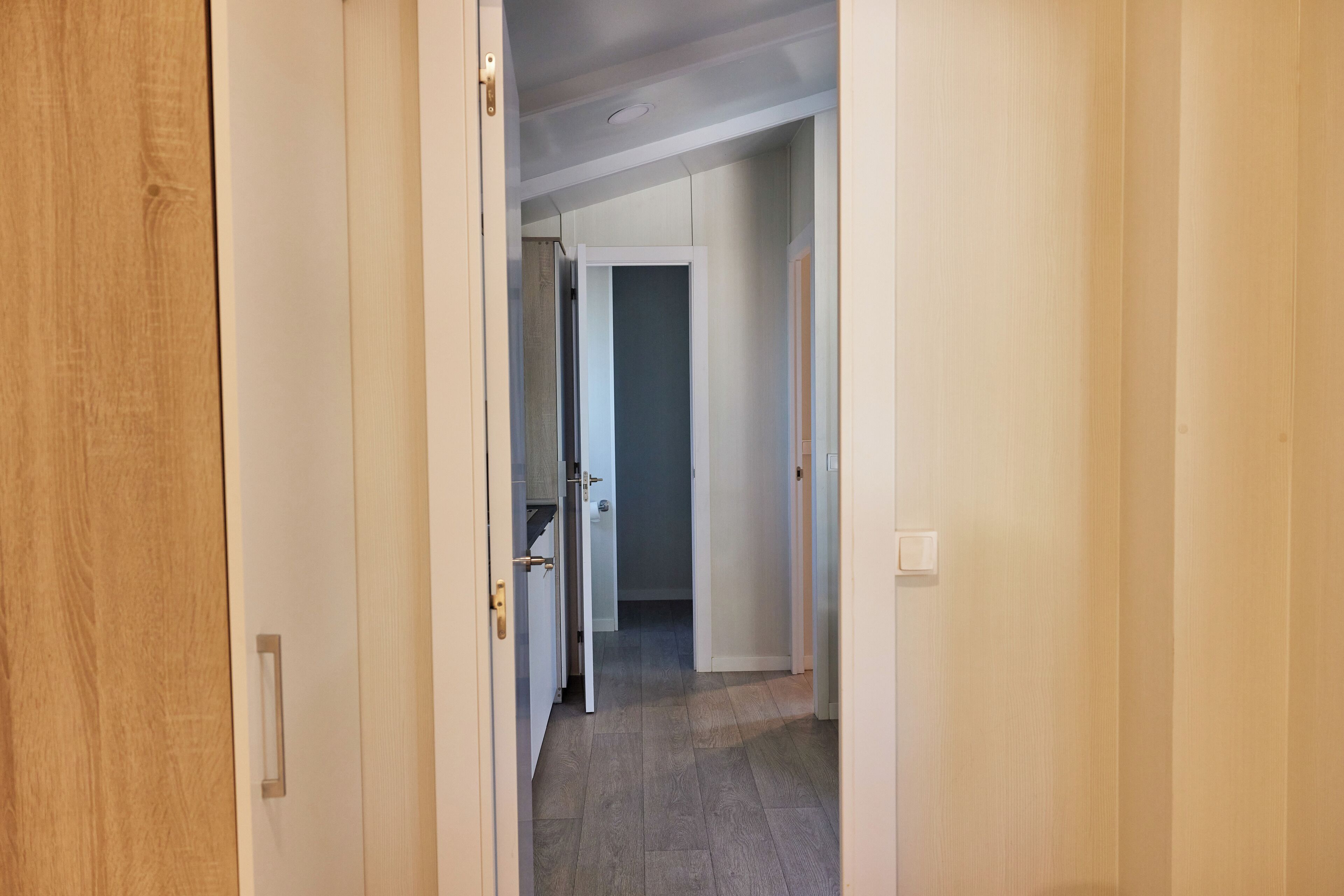 A hallway with wooden doors and a tiled floor.