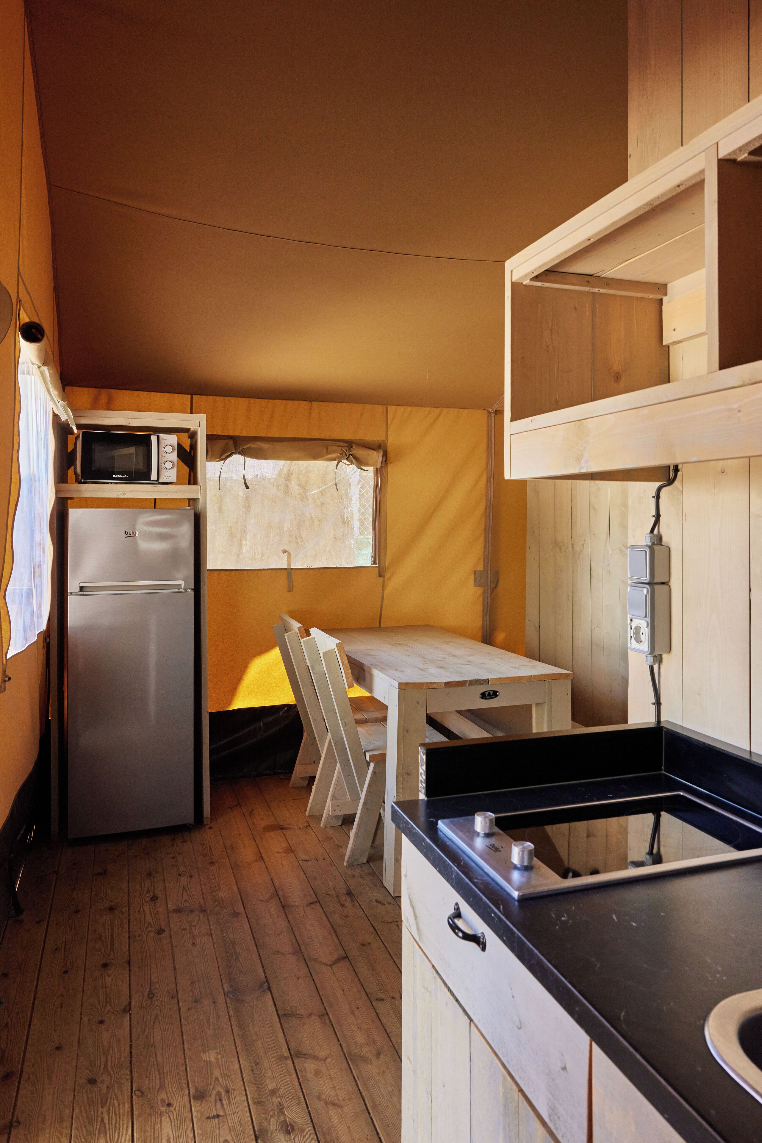 A compact kitchen with a refrigerator, microwave, and a small dining table.