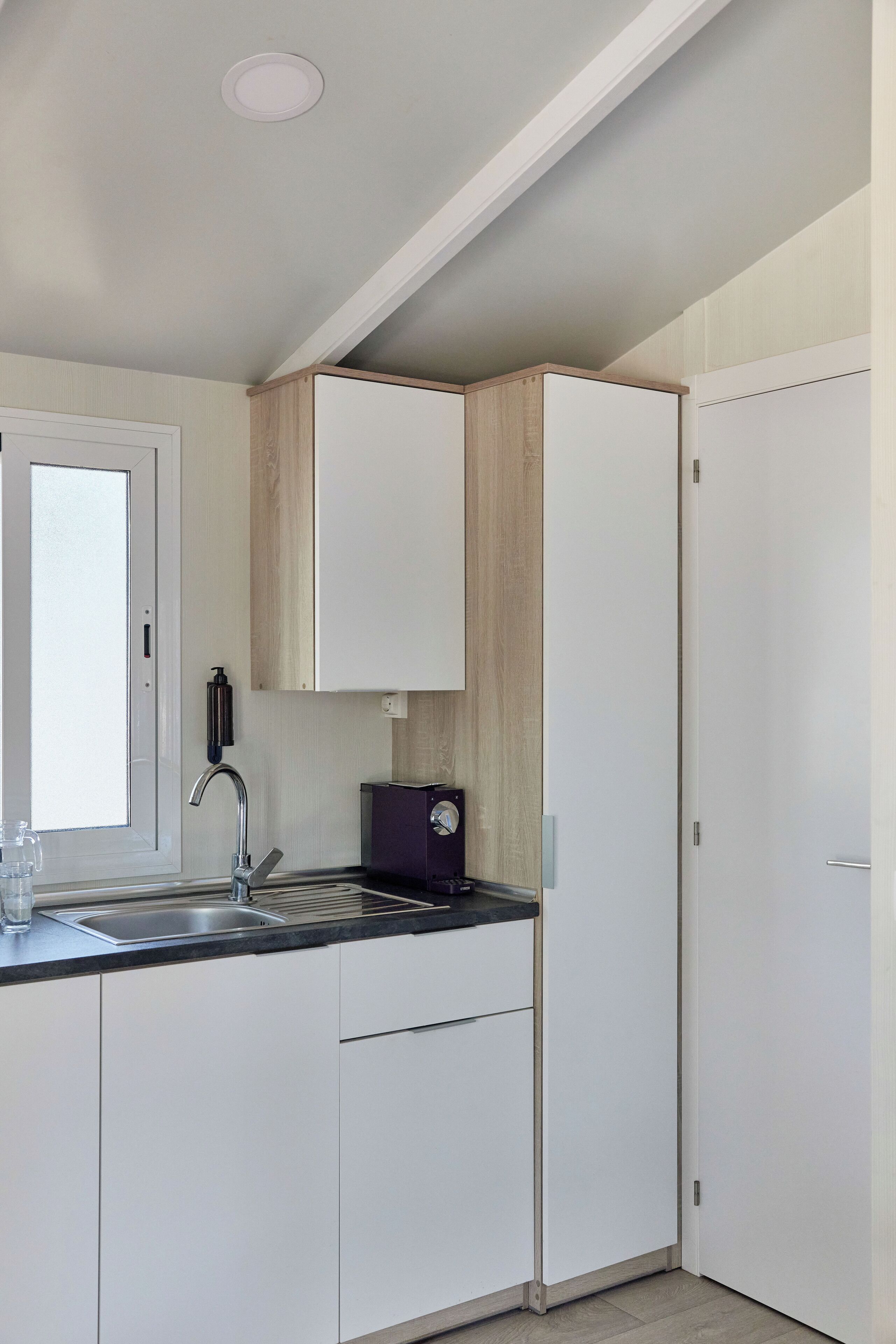 Una cocina moderna con armarios blancos, encimera negra y pileta de acero inoxidable.