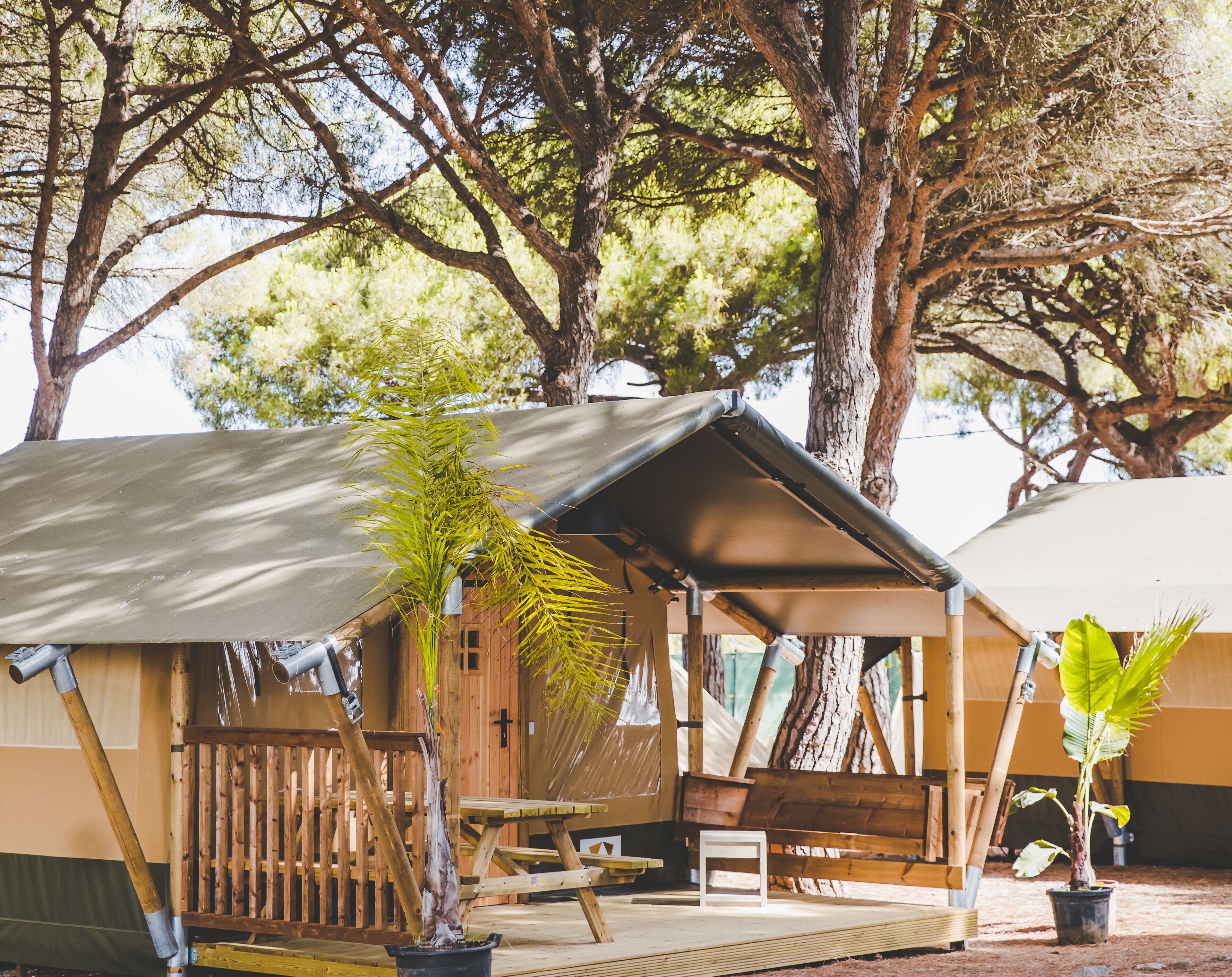 A wooden cabin with a covered porch, a bench, and a table.