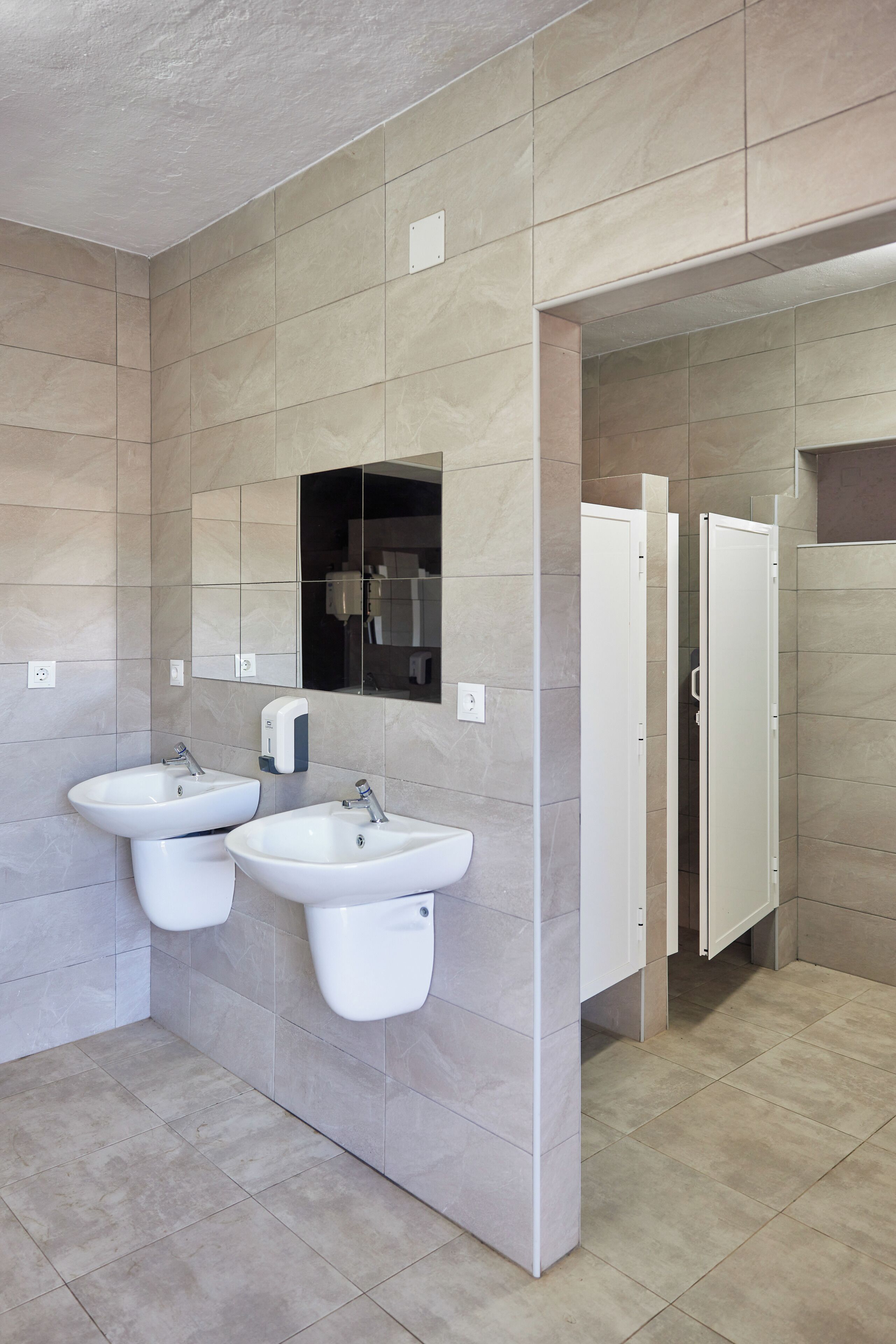 Une salle de bain moderne avec deux lavabos, un miroir et des toilettes séparées.