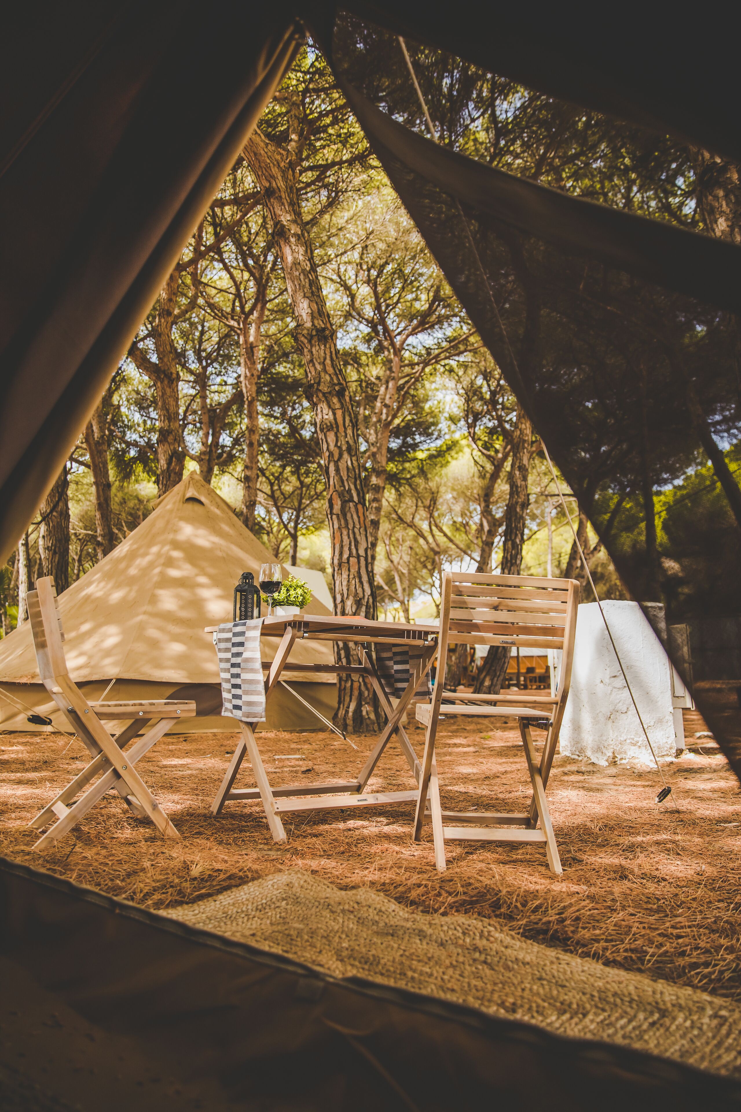 A tent with a table and chairs set up in a forest.