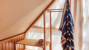 A small attic room with wooden flooring, a wooden shelf, and a hanging towel.