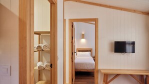 A bedroom with a wooden bed, a TV mounted on the wall, and a wooden bench. - TAIGA Conil (Conil de la Frontera)