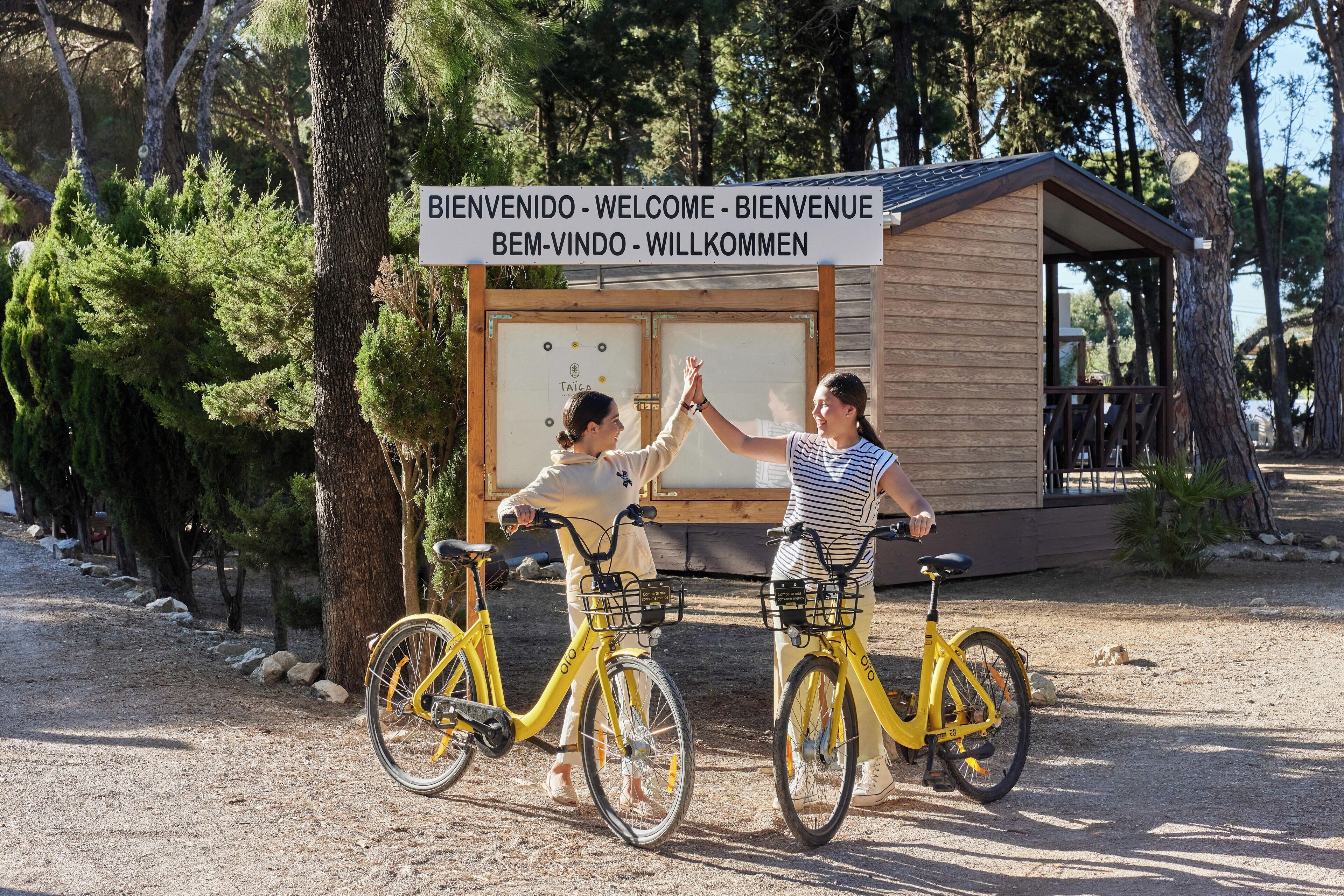 Dos personas chocando los cinco cerca de una estructura de madera con un letrero en varios idiomas.