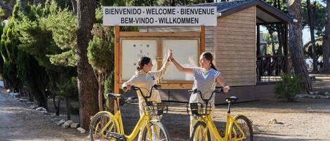 Two people high-fiving near a wooden structure with a sign in multiple languages.