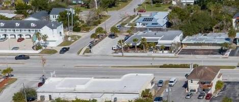 An aerial view of a residential area with houses, roads, and a large building with a white roof.