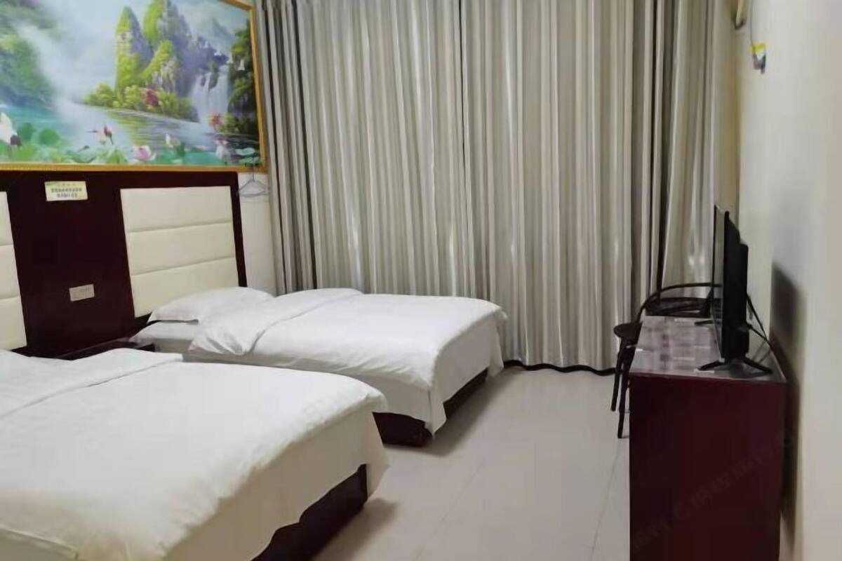 A hotel room with two beds, a desk with a computer, and a painting on the wall.