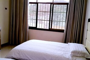 A room with a bed, a window with metal bars, and curtains.