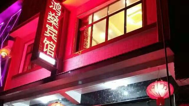Un edificio con letrero de neón y faroles rojos.
