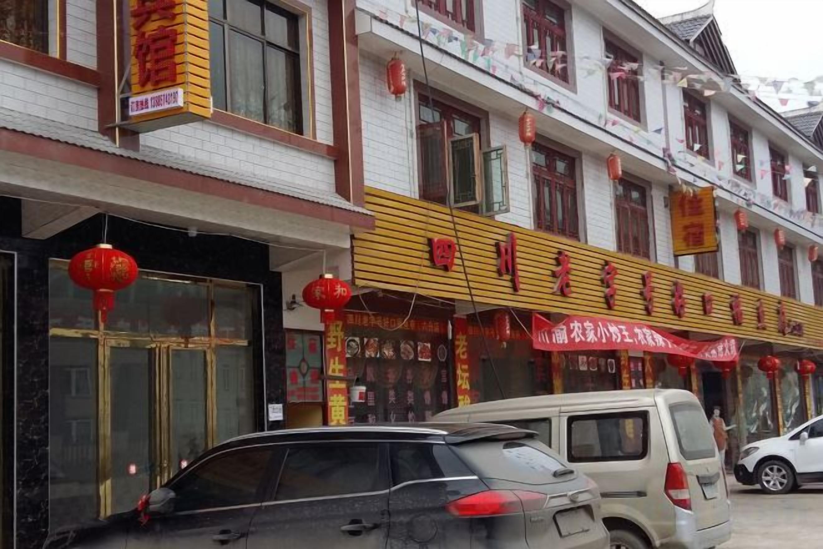 A building with multiple storefronts, including a restaurant with a yellow awning and red signage.
