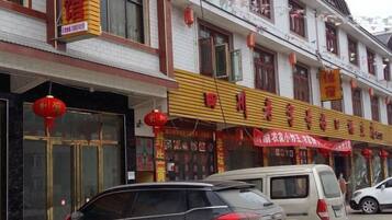 A building with multiple storefronts, including a restaurant with a yellow awning and red signage.