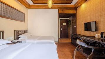 Habitación de hotel con dos camas, techo de madera, televisor y una mesita con hervidor.