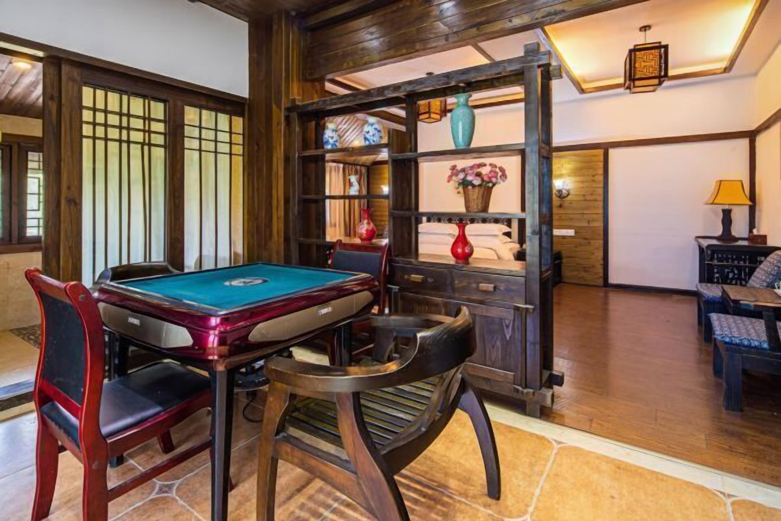 Une table de billard avec des chaises, une étagère avec des objets décoratifs et une lampe.