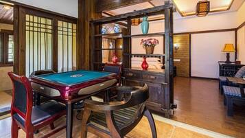 Une table de billard avec des chaises, une étagère avec des objets décoratifs et une lampe.