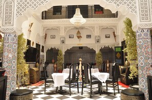 A dining area with ornate white and black patterned walls, a chandelier, and a checkered floor. - Riad La Porte d'Or & Spa (Marrakech)