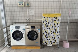 A laundry area with two washing machines, a drying rack, and a mop. - Pebble Motel (Guangzhou Conghua Street North Highway Intersection) (Guangzhou)