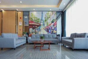 A lobby with a large mural, grey sofas, a wooden coffee table, and a reception desk. - Pebble Motel (Guangzhou Conghua Street North Highway Intersection) (Guangzhou)