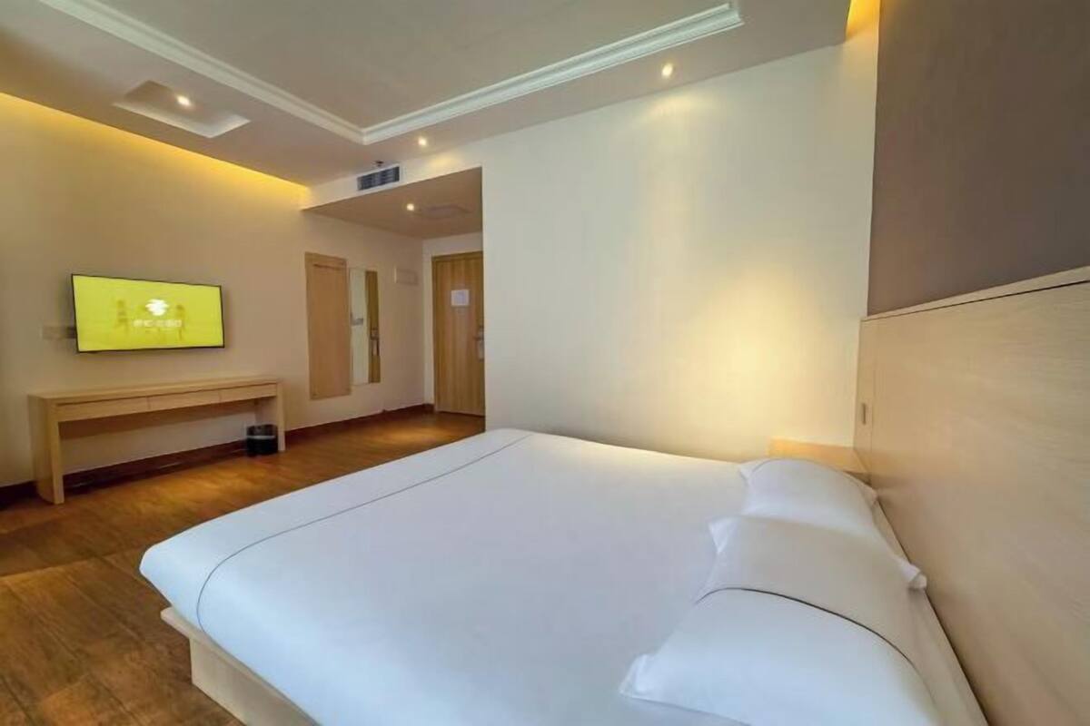 A hotel room with a bed, a TV, a desk, and a door.