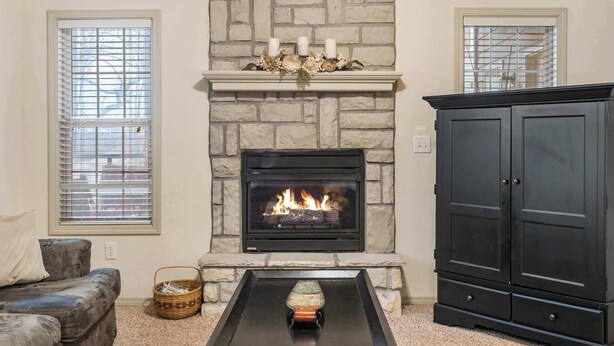 A living room with a stone fireplace, a black cabinet, and a gray couch. - Silver Dollar Hideaway in Stonebridge Community (Branson West)