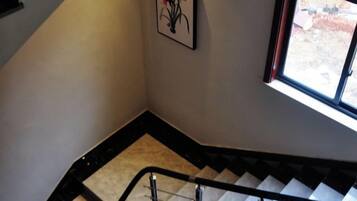 Una escalera con barandilla, un cuadro enmarcado en la pared y una ventana que da a vistas del exterior.